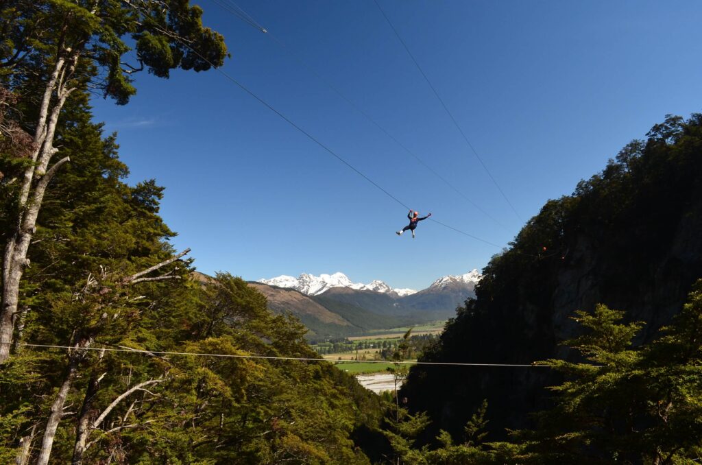 Zipline rider high above the valley, snow-capped Humboldt Mountains behind